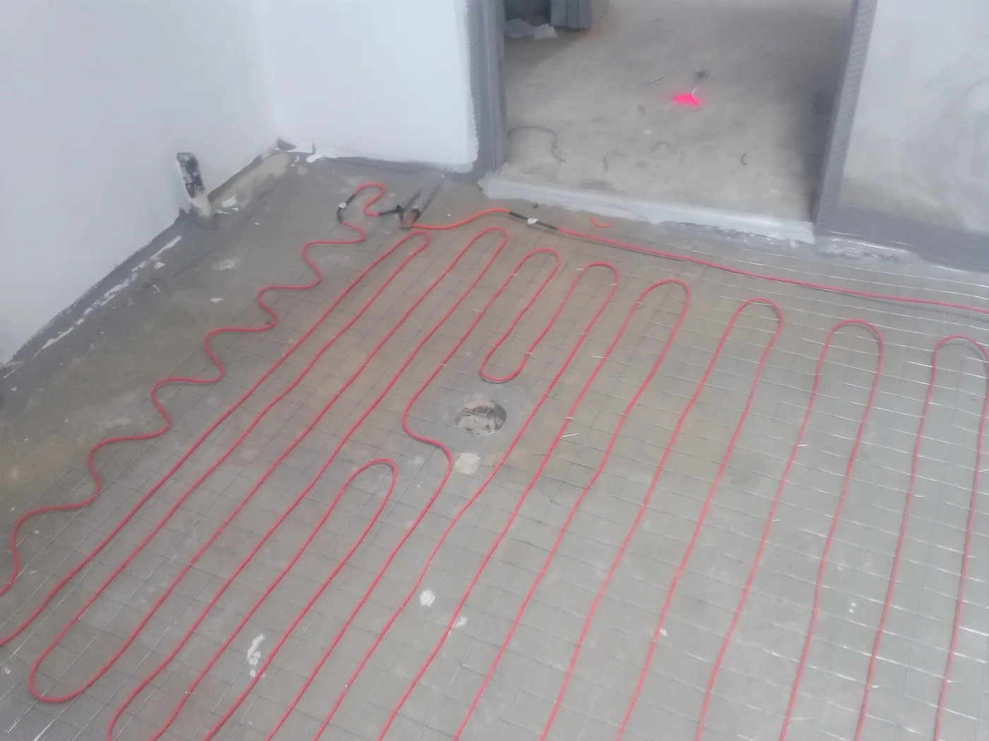 Cable set out on a stripped apartment floor, with the doorway into the next room left clear.