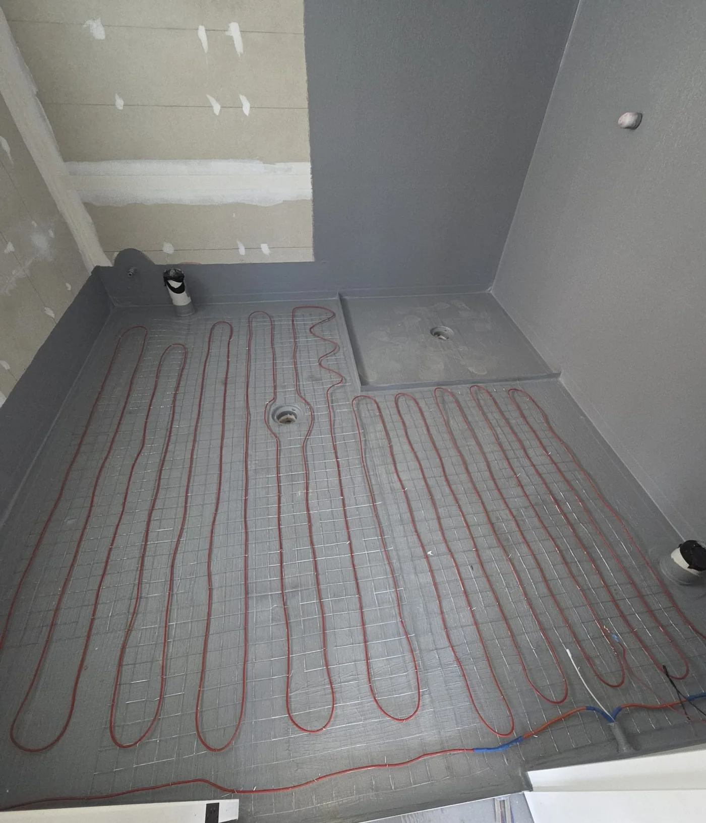 Cable run across a bathroom floor taken back to the slab, with the shower base formed and the wastes set in.