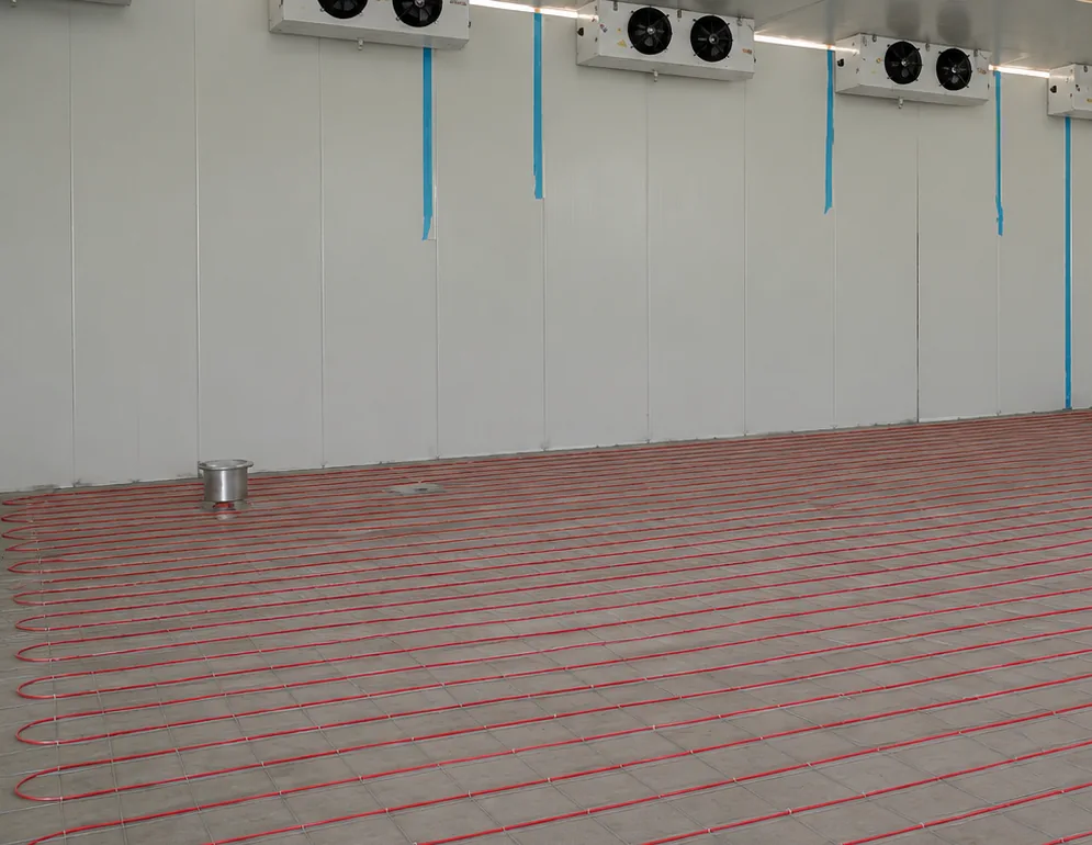 Cable laid on mesh across a cold store floor, with the panel walls and the evaporators already in.