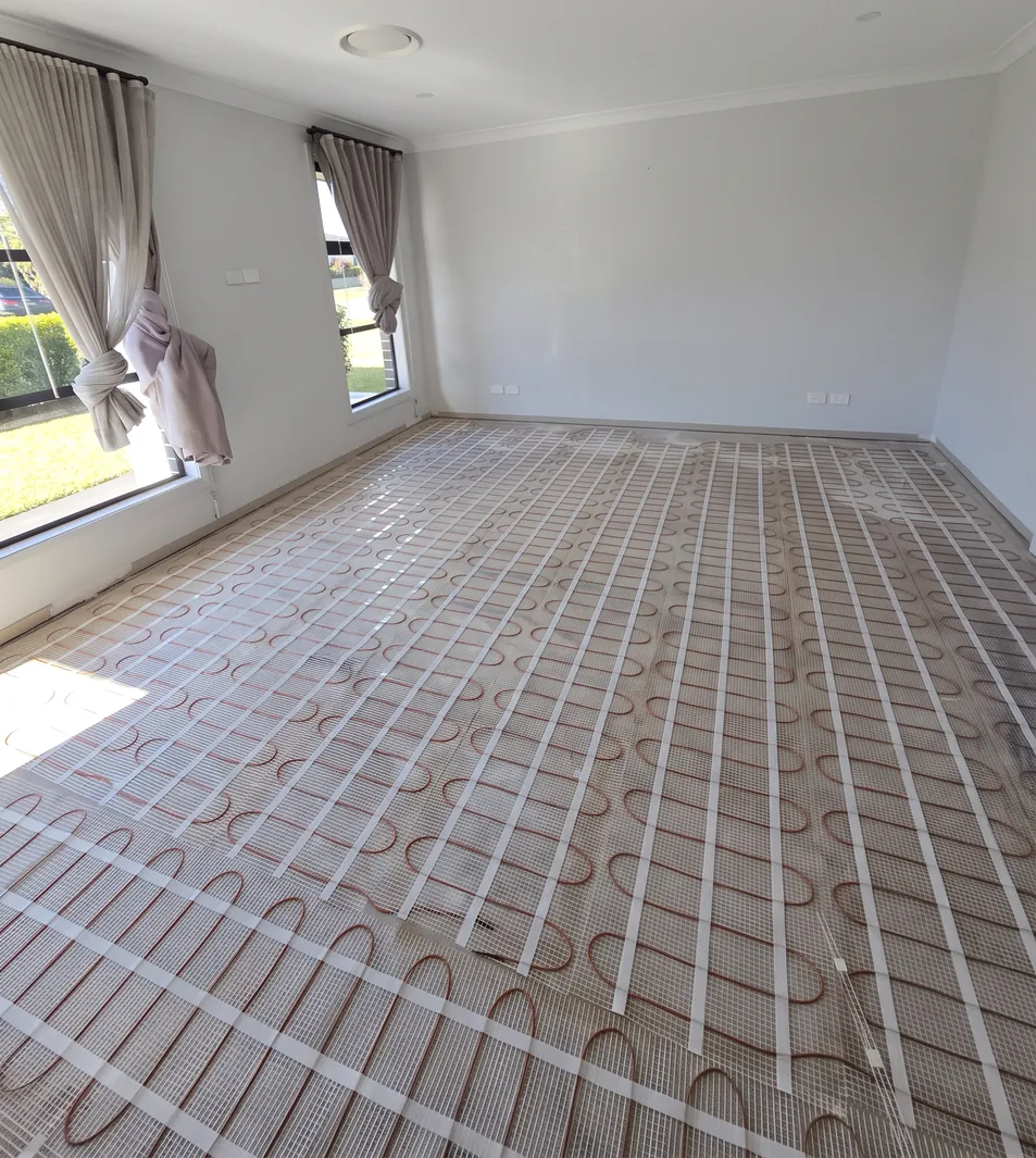 A heating mat rolled out over the existing floor of a finished room, with the curtains and windows still in place.