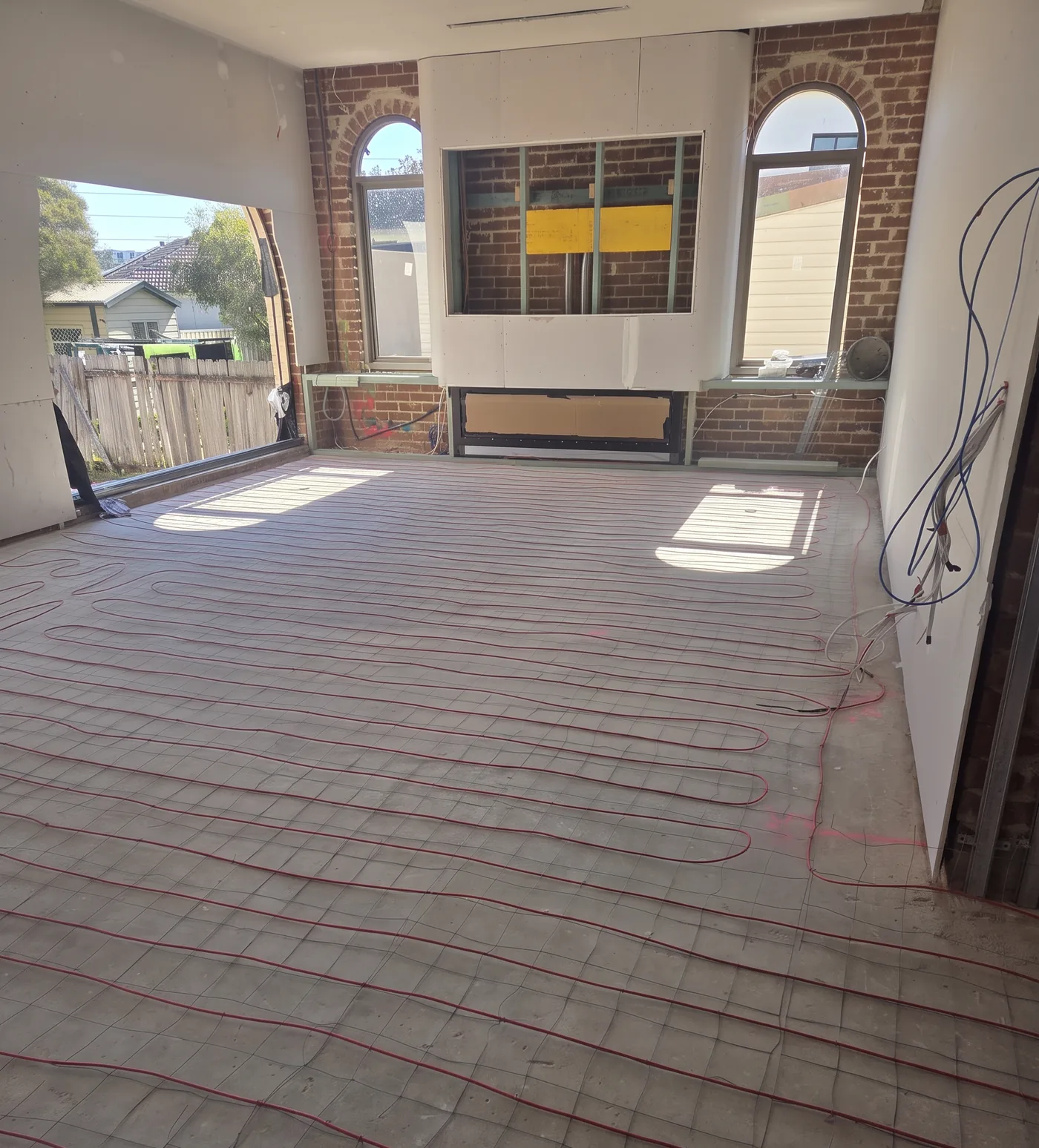 Cable set out across the floor of a room stripped back to its brickwork during a renovation.