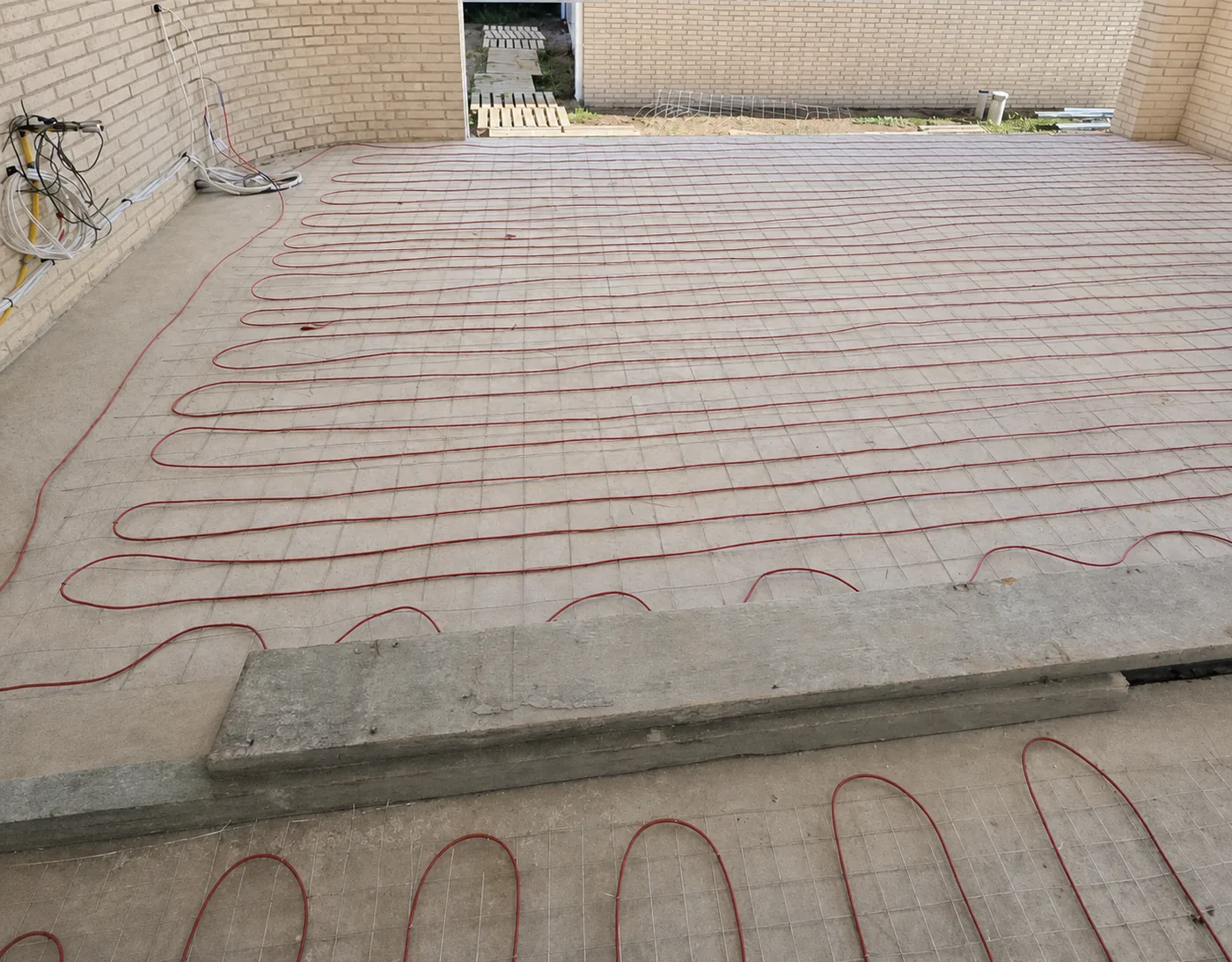Heating cable laid out across the floor of a new house, with the brickwork up and the screed still to come.