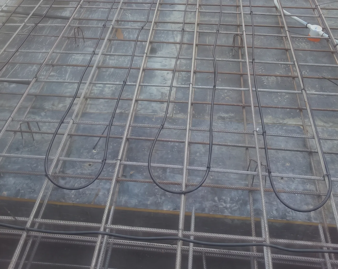 In slab heating cable tied to the top layer of reinforcing mesh across a house slab, ready for the concrete.